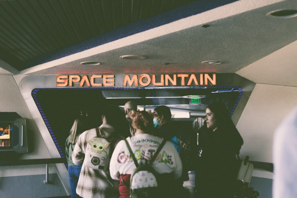 a group of people standing in front of a space mountain sign